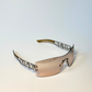 Close-up of Dior Diorlywood sunglasses showcasing engraved logo and brown gradient lenses